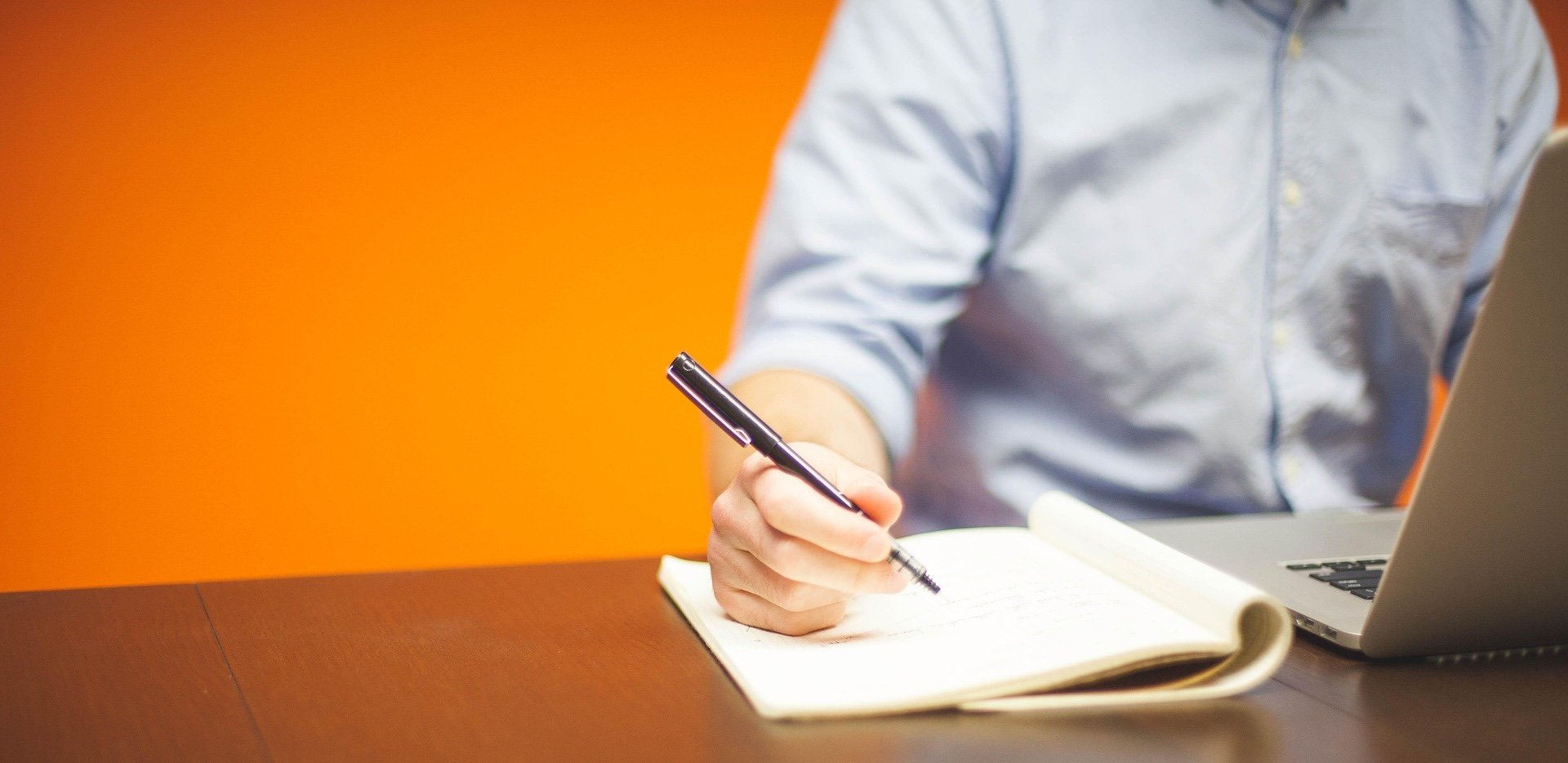 person sitting at table writing in notebook